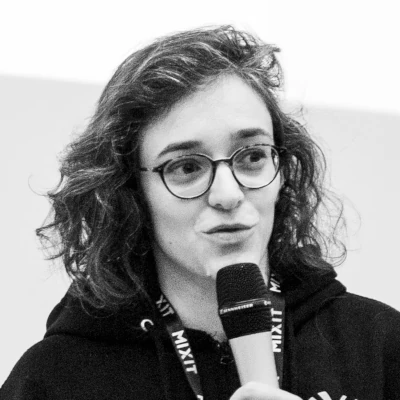 Photo de Marie-Alice en noir et blanc qui parle dans un micro pendant la conférence MiXiT